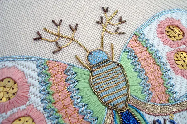 This needlepoint butterfly is a highly stylistic depiction, a blend of stitches and thread types.