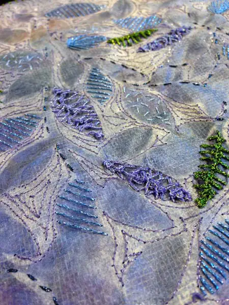 Sam used a variety of stitches in a combination of hand and machine embroidery using metallic threads on silk paper. Kreinik Fashion Twist is used for the machine stitching, while various sizes (thicknesses) of Kreinik Braids are used for the hand embroidery.