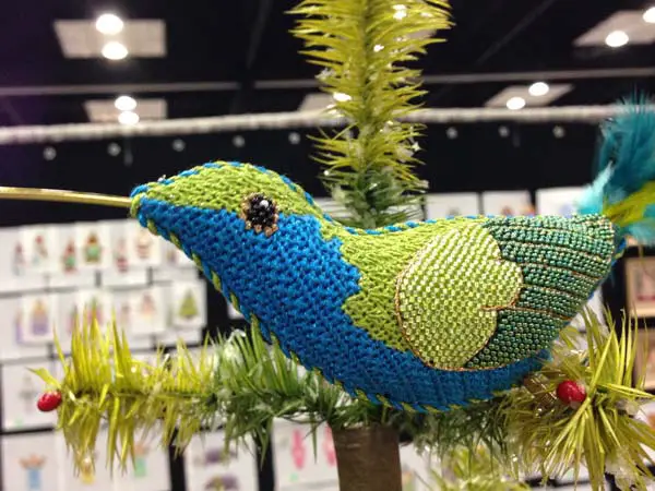 A variety of stitches, threads and ephemera (wire, feathers) come together to make this stunning needlepoint hummingbird. Painted canvas design by Labors of Love design company.