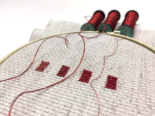 Cross stitches of Kreinik Braids and Blending Filament to show the various degrees of metallic effects you can create.
