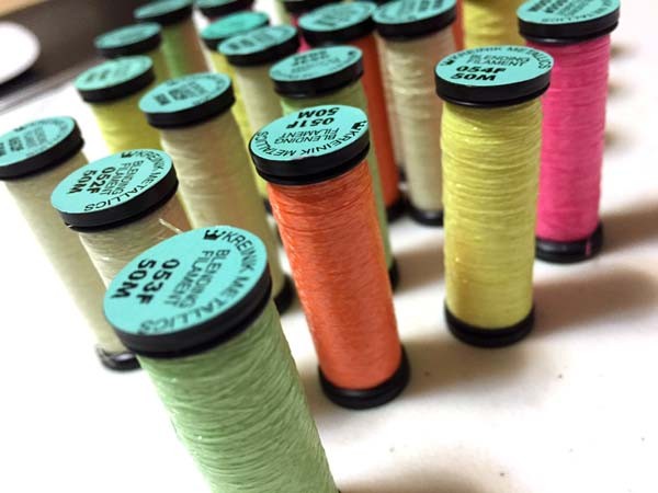 Kreinik Blending Filament is a thin thread you add to cotton floss or knitting yarn for a lightweight look. The glowing colors carry an "F" after the color number, as in 053F.
