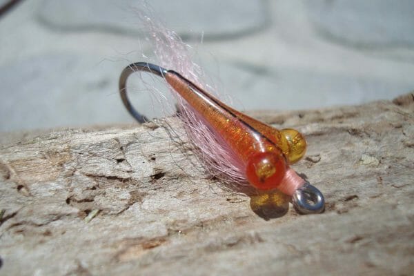 This fly fishing lure looks alien to me, but I bet it's irresistible to fish. The body is wrapped with metallic threads, then covered with a clear epoxy, which lets some of the shimmer come through. Creative mix of materials.