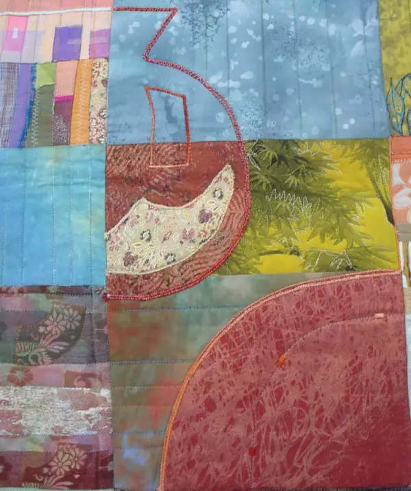Close up look at the beautiful blend of fabrics, patterns, stitches, and threads in Eleanor's Pomegranates quilt.