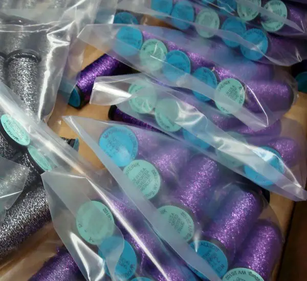 Another photo from the Kreinik thread factory, showing purple spools of Tapestry #12 Braid (a popular thread for needlepoint) ready to be shipped to stores. Purple looks good next to gray, doesn't it?